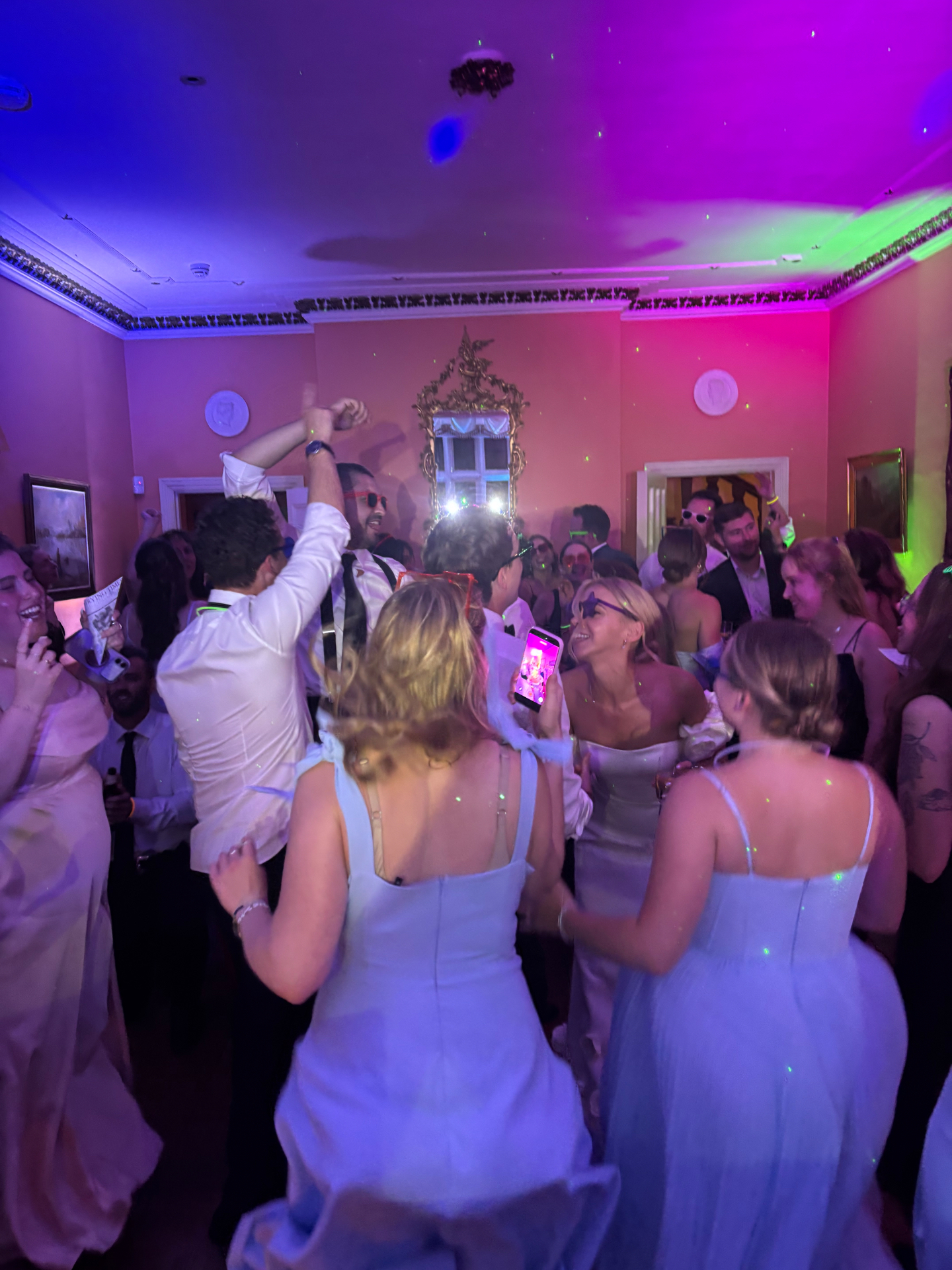 Wedding guests dancing under purple, pink and green DJ lighting at a recent spiNZ 360 Events celebration.